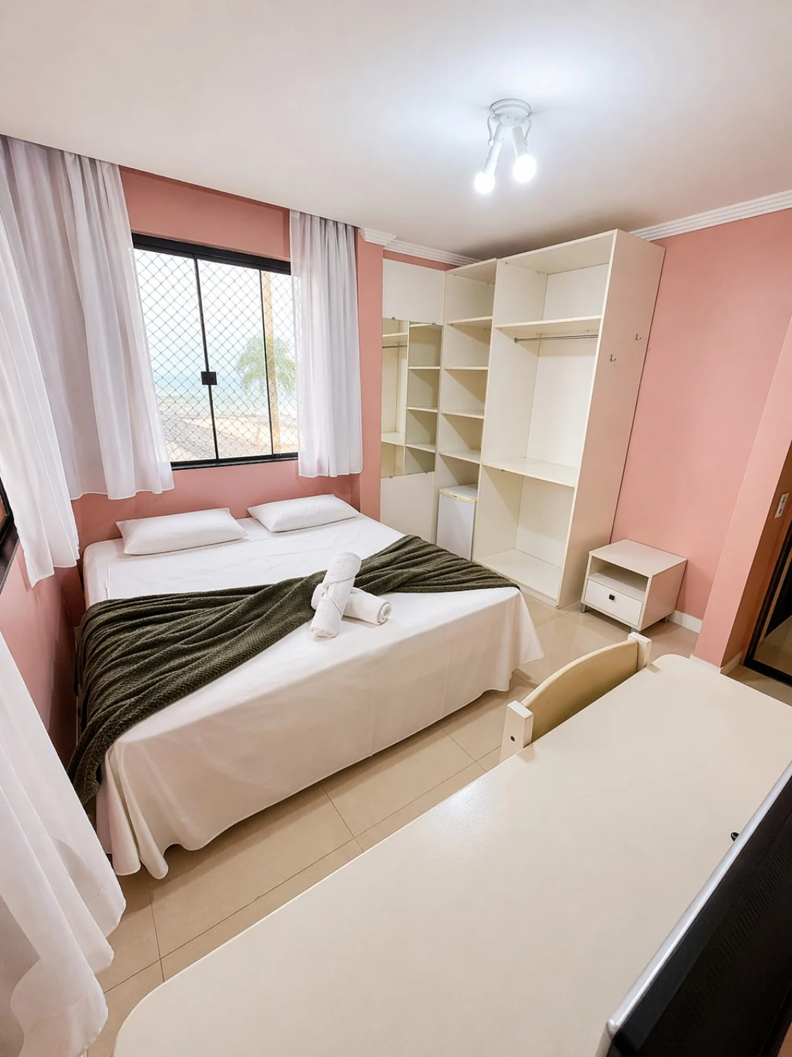 Quarto privativo com mesa de apoio, armário e vista